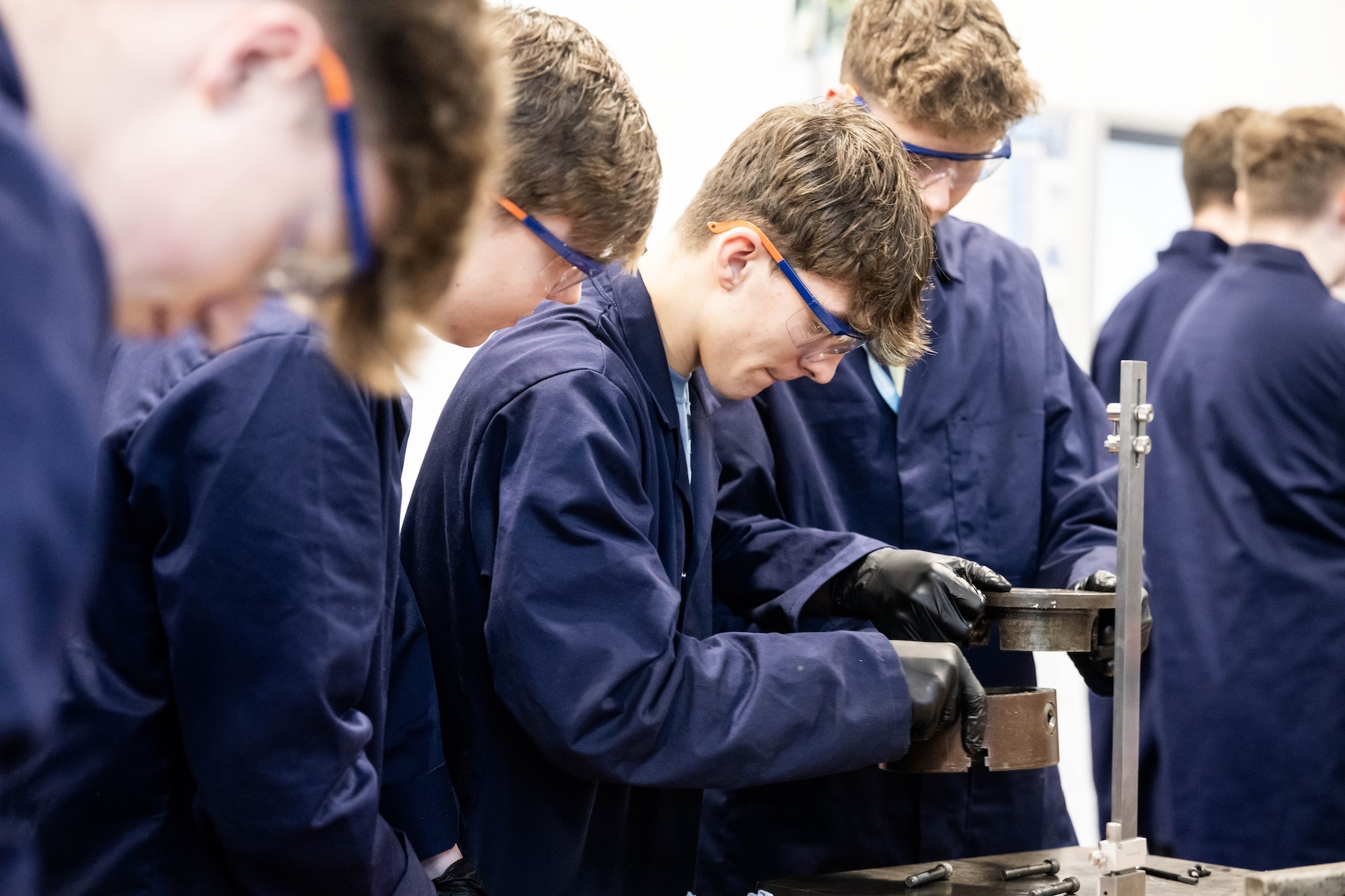 Photo of two engineering students in protective clothing an glasses inspecting metal parts